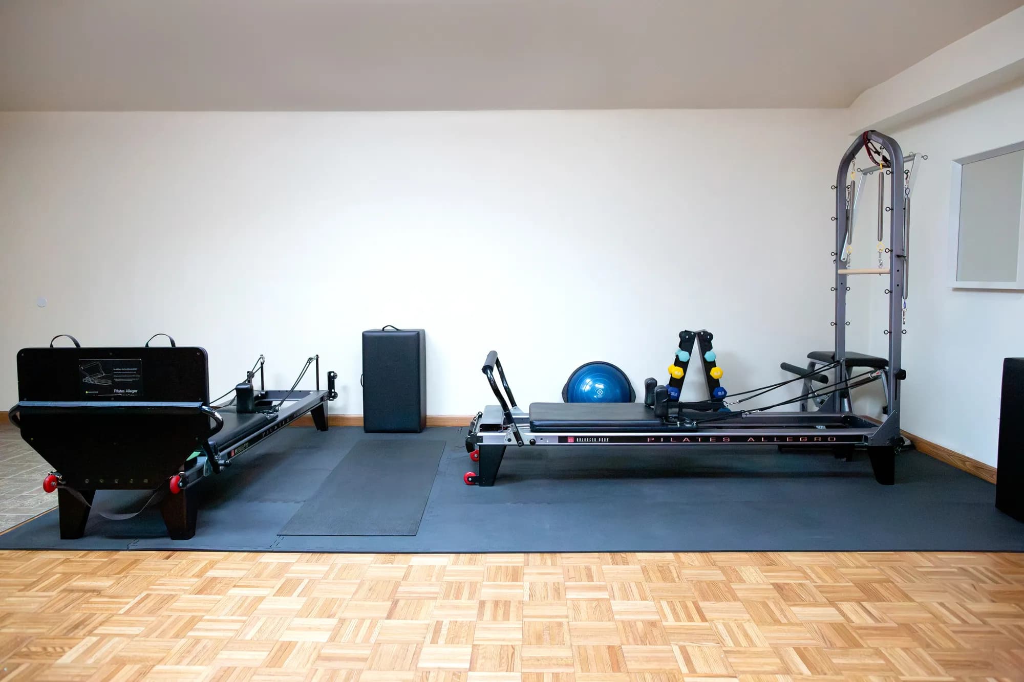 The Sculpt & Stretch studio, with two reformers and a tower on a padded floor